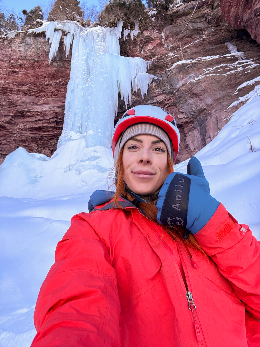 Sofia at the base of an ice climb giving a thumb's up sign